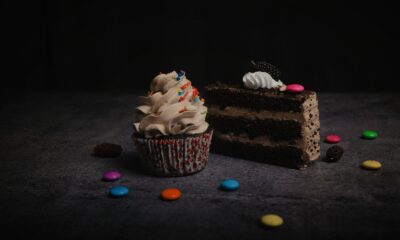 Close-up of a chocolate cake slice and cupcake with sprinkles and candies, perfect for sweet cravings.