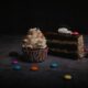 Close-up of a chocolate cake slice and cupcake with sprinkles and candies, perfect for sweet cravings.