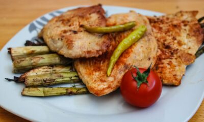 A savory plate of grilled chicken with asparagus and a fresh tomato.