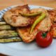 A savory plate of grilled chicken with asparagus and a fresh tomato.