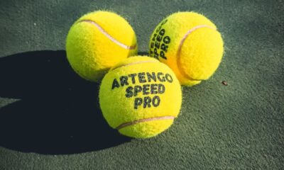 Three Artengo Speed Pro tennis balls on a green court, emphasizing leisure and sport.