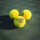 Three Artengo Speed Pro tennis balls on a green court, emphasizing leisure and sport.