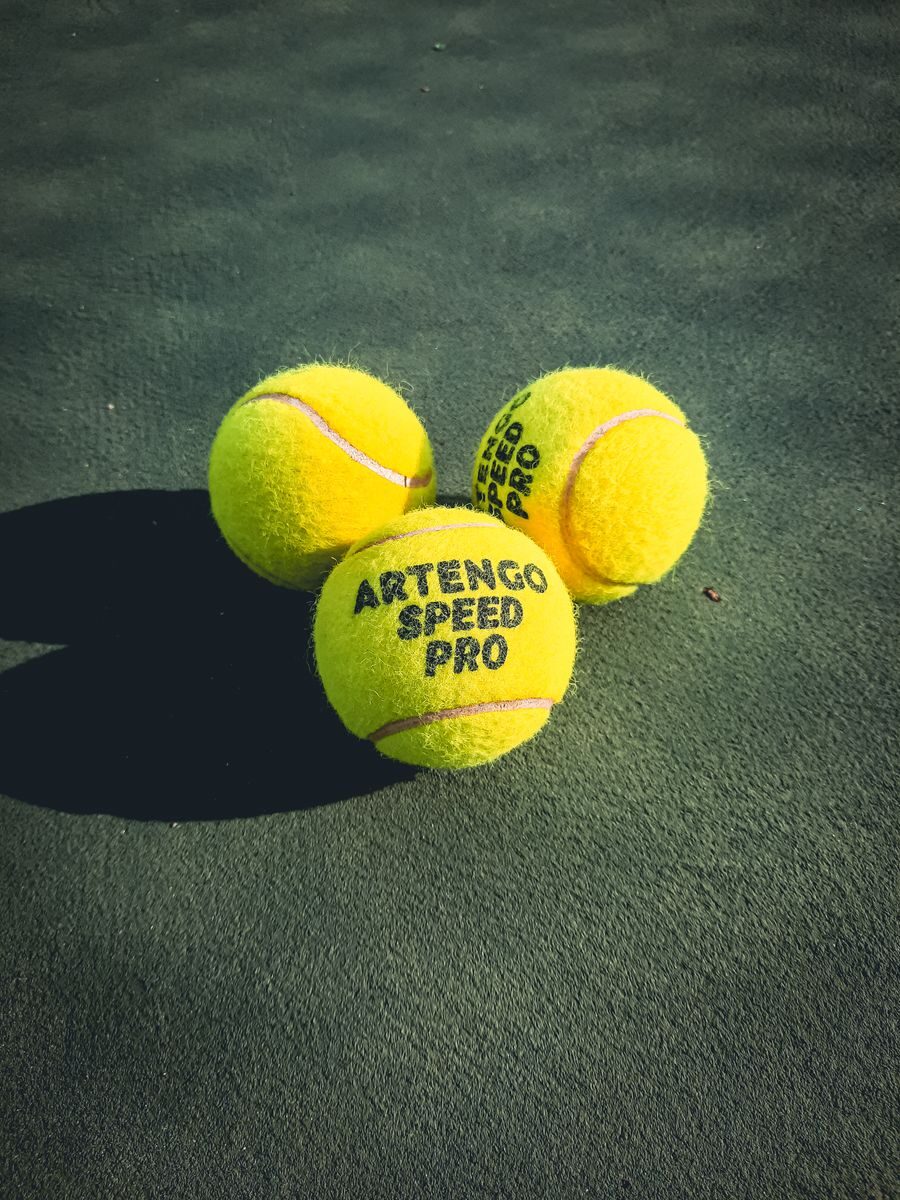Three Artengo Speed Pro tennis balls on a green court, emphasizing leisure and sport.