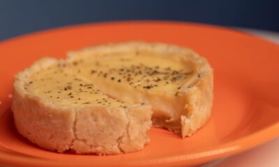 Close-up of a savory quiche with herbs on a vibrant orange plate.