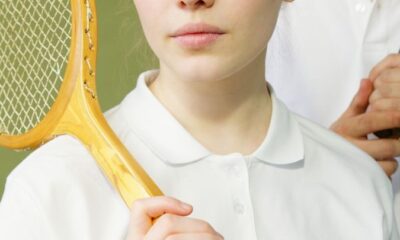 Portrait of a young woman in sportswear holding a vintage tennis racket, looking confident and focused.