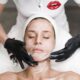 Woman receiving a facial treatment at spa, with beautician applying mask in a relaxing setting.