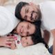 Happy family portrait with parents and baby, showcasing love and togetherness indoors.