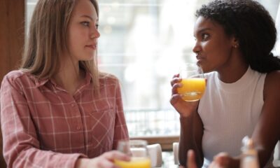 Two women enjoying a casual conversation while drinking orange juice in a café.