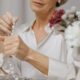 Sophisticated mature woman examining pearl necklace at an elegant table setting.