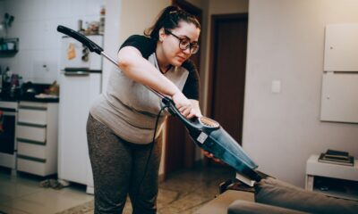 A woman vacuuming a couch in a cozy living room setting, emphasizing daily housework.
