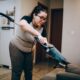 A woman vacuuming a couch in a cozy living room setting, emphasizing daily housework.