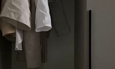Linen clothes hanging on wooden hangers in a softly lit closet, showcasing neutral tones and textures.