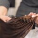 A hairdresser skillfully combs wet hair, focusing on smooth styling in a salon setting.