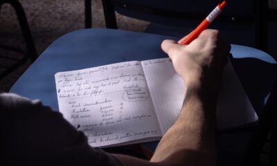 A student takes notes in a classroom in Buenos Aires. Natural lighting highlights the writing process.