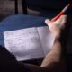 A student takes notes in a classroom in Buenos Aires. Natural lighting highlights the writing process.