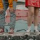 Two people in stylish streetwear against a graffiti backdrop, highlighting urban fashion with jeans and sneakers.