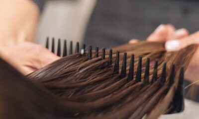 A hairdresser skillfully combs wet hair, focusing on smooth styling in a salon setting.