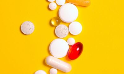 Colorful pills and tablets scattered on a vivid yellow background, symbolizing medicine and health.
