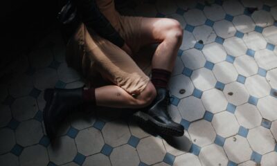 An artistic shot of a woman sitting on a vintage patterned tiled floor, showcasing fashion and style.