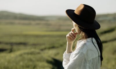 Woman in a hat gazes over the picturesque countryside under a sunny sky.