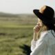 Woman in a hat gazes over the picturesque countryside under a sunny sky.