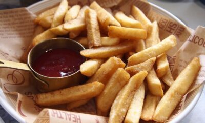 A plate of golden, crispy French fries served with a side of ketchup.