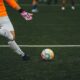 A soccer goalkeeper prepares to kick a colorful ball on a grass field.
