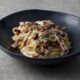 Mouth-watering spaghetti carbonara with creamy sauce and crispy bacon bits served in a bowl.