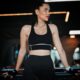 Woman in athletic wear exercising in a gym with contemporary lighting.