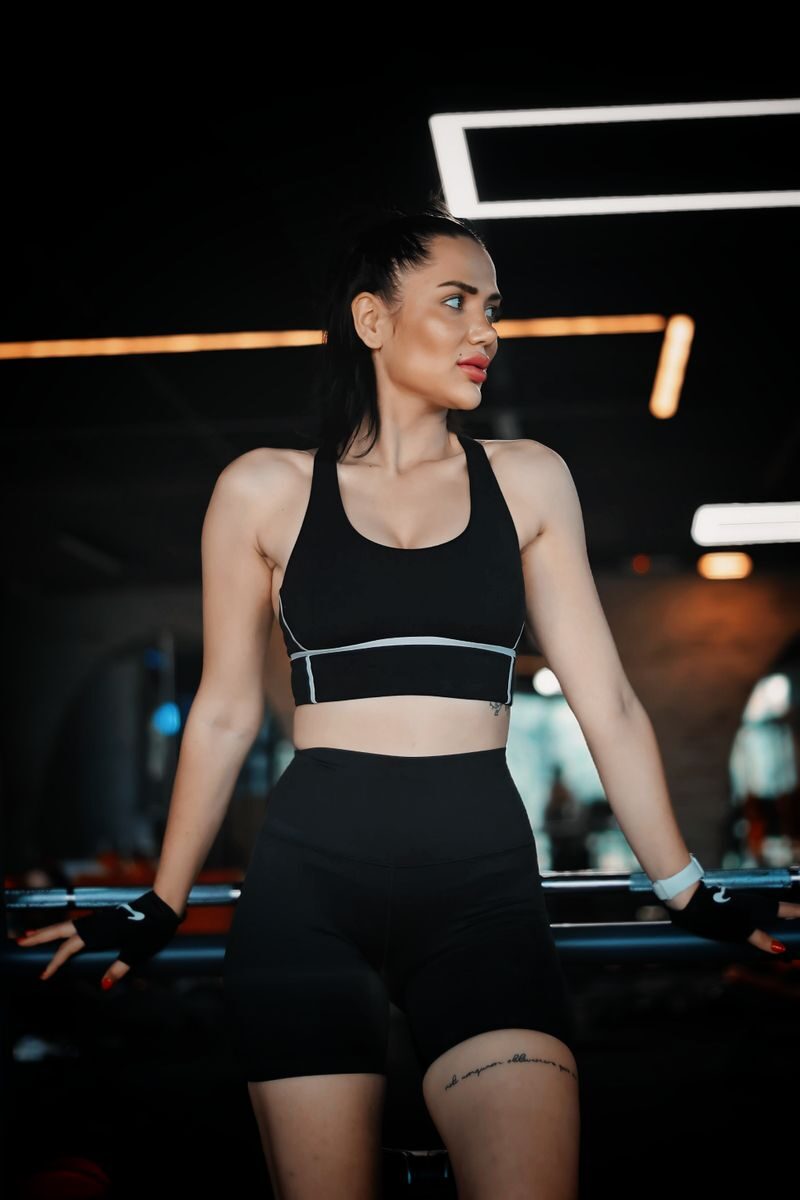Woman in athletic wear exercising in a gym with contemporary lighting.