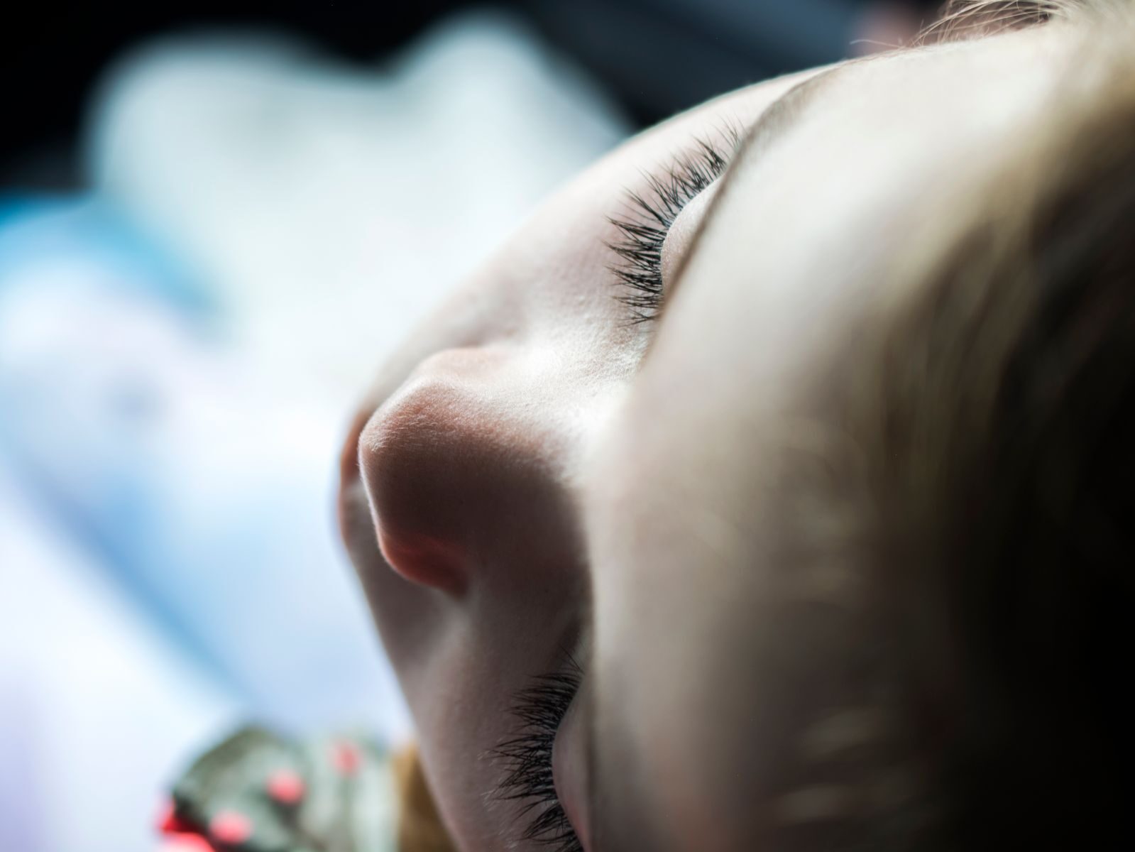 Intimate close-up photo of a child's face in soft light, focusing on serene eyelashes.