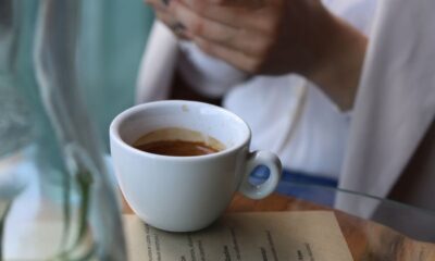 Woman with a coffee and smartphone at a cafe table, creating a cozy and modern ambiance.