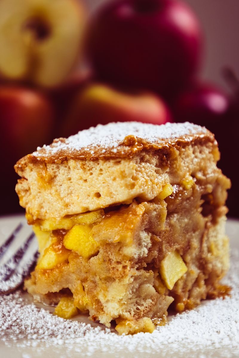 Scrumptious slice of apple cake dusted with powdered sugar, perfect for dessert lovers.