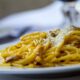 Close-up of spaghetti carbonara topped with grated Parmesan cheese on a plate, perfect for Italian cuisine lovers.